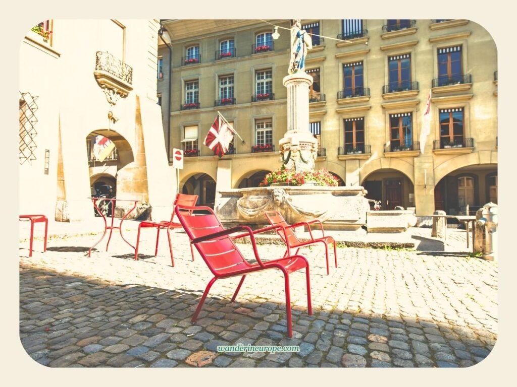 Visiting Bern Cathedral: Expectations, Tips, Things to See 6 Red public chairs in front of Bern Cathedral and beside Mosesbrunnen in Bern, Switzerland