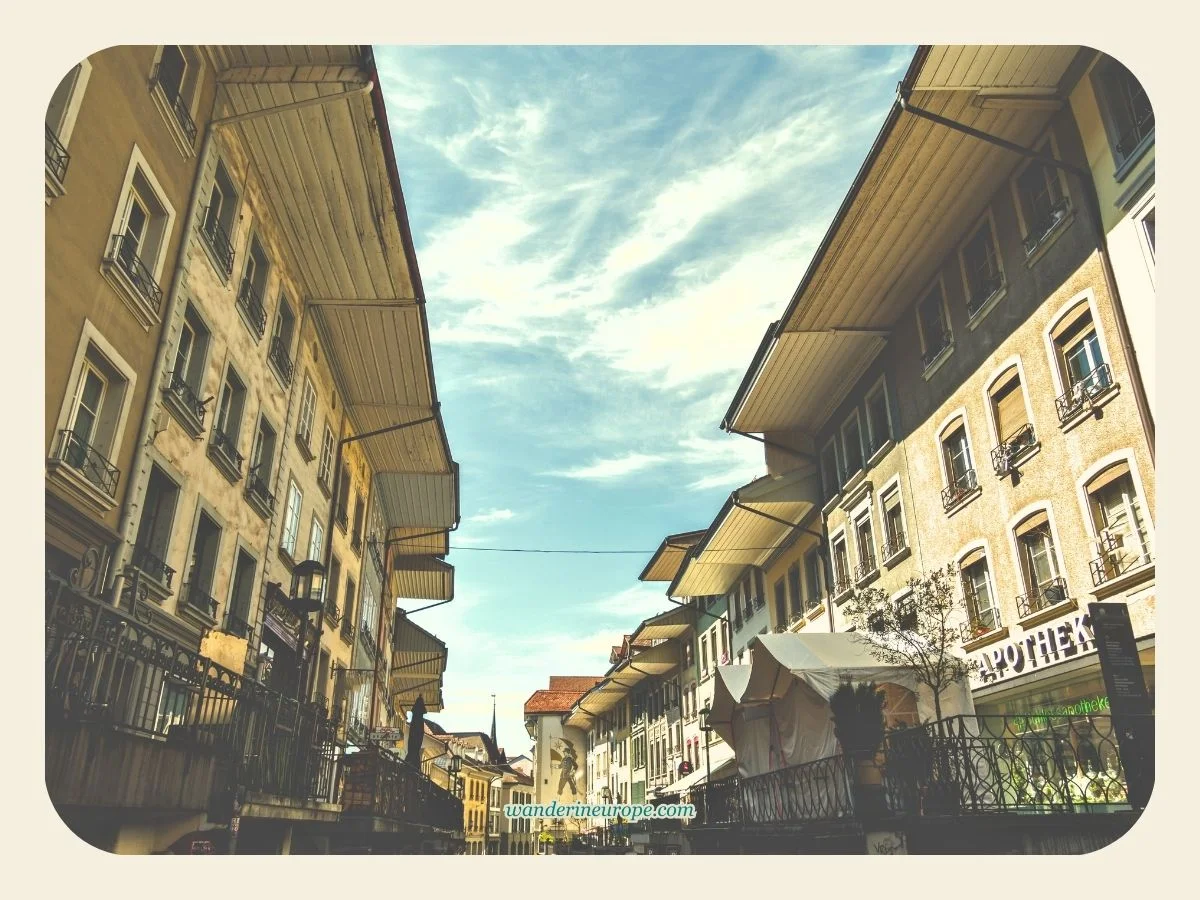 The houses, raised pavement, and a mural holding the coat of arms of Thun in Obere Hauptgasse in Thun, Switzerland